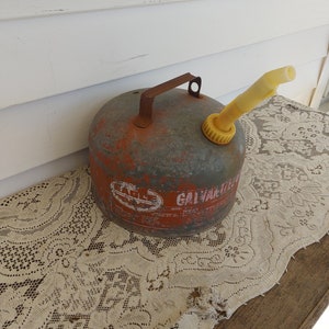 May include: A vintage red metal gas can with a yellow spout and a handle. The can has a label that says "Galvanized" and "Model 2-2".