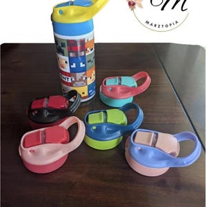 May include: A cylindrical water bottle featuring a grid of pixelated character faces and the text TNT, topped with a yellow flip-top lid. Five additional replacement flip-top lids in various colors including black, pink, blue, and purple are included.