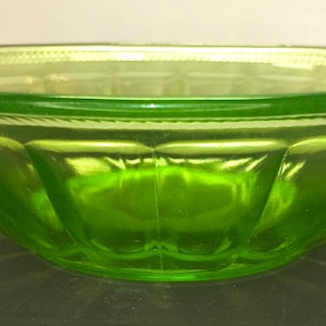 May include: A green glass bowl with a scalloped design. The bowl has a rounded shape with a wide rim and a textured pattern on the exterior. The glass is a vibrant, translucent green color.