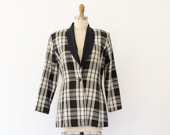 Könnte beinhalten: Ein schwarz-weiß karierter Blazer mit schwarzem Kragen und einem einzigen Knopfverschluss. Der Blazer befindet sich auf einem Mannequin.