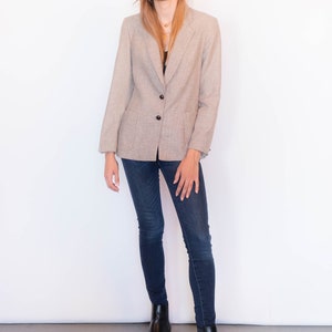 Puede incluir: Una mujer con un blazer marr&oacute;n claro con cierre de bot&oacute;n, jeans azul oscuro y botines negros.