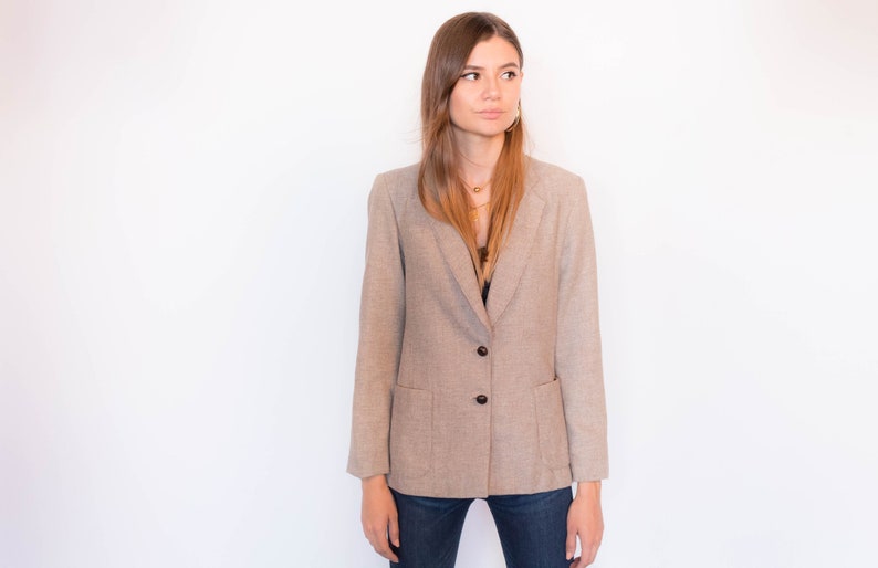 Puede incluir: Una chaqueta marr&oacute;n claro con un cierre de bot&oacute;n &uacute;nico y dos bolsillos. La chaqueta est&aacute; hecha de una tela texturizada y tiene un ajuste relajado.
