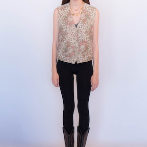 May include: A woman wearing a floral patterned vest, black leggings, and brown cowboy boots.