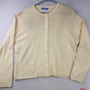 May include: Cream-colored cardigan sweater with a round neckline and long sleeves. The sweater has a button-up front and is adorned with small, evenly spaced pearl-like embellishments. The brand name "Pendleton" is visible on a small tag near the neckline. The sweater is hanging on a blue hanger.