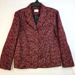 May include: A burgundy blazer with a textured weave pattern. The blazer has a notched collar, a single-button closure, and long sleeves. The lining is black, and the brand name "KOREN" is visible on a label.