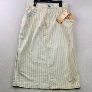 May include: A high-waisted midi skirt in a light cream and pale blue vertical striped pattern. The skirt features a button and zipper fly closure, two side pockets, and a Levi's brand tag attached to the waistband with the text Size 14 visible.