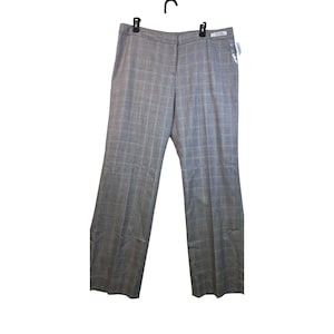 May include: Gray plaid trousers hanging on a black hanger. The pants have a straight leg design and a classic plaid pattern in shades of gray and blue. A white tag is attached to the pants.