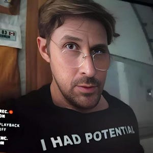 Pode incluir: Uma caneca de cerâmica branca com uma alça preta e o texto "But First, Coffee" em negrito preto. A caneca está sobre uma superfície branca, mostrando seu design limpo.