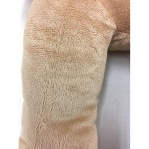 May include: Close-up of a plush, beige-colored stuffed animal. The fur is soft and textured, with a slight sheen. The image focuses on the details of the fabric and the gentle curves of the toy.