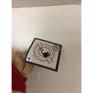 May include: A baseball-themed tag with the MLB logo, a baseball graphic, and the words "Genuine Merchandise". The tag is attached to a tan and red plush toy.