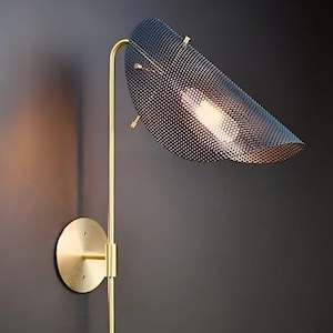 Peut inclure: Applique murale moderne avec une finition en laiton. La lampe est dotée d'un abat-jour perforé bleu foncé et d'un bras incurvé. La base ronde est fixée au mur. Le design est minimaliste et élégant, adapté à l'éclairage intérieur.