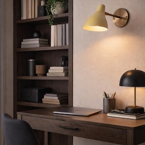 May include: A home office setup with a dark wood desk, chair, and built-in bookshelf. A yellow wall-mounted lamp and a black desk lamp provide light. The desk holds a laptop, pens, and books. A small plant sits on the bookshelf.