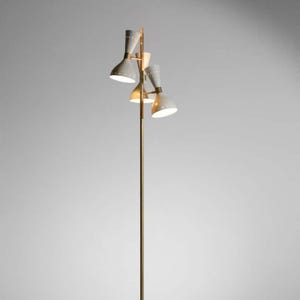 May include: A tall, brass-coloured floor lamp with four cone-shaped light fixtures. The lampshades are light grey with small, evenly spaced holes. The lamp has a black base and a power cord.
