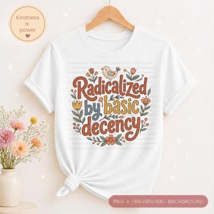 Op de afbeelding: Wit t-shirt met de tekst "Radicalized by basic decency" in een retro lettertype, omringd door bloemen- en vogelillustraties. Het shirt wordt gepresenteerd op een houten hanger.