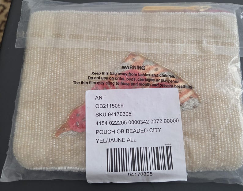 May include: A beaded pouch in a clear plastic bag. The pouch is a light beige color and has an embroidered design in shades of red, orange, and yellow. The pouch is labeled "POUCH OB BEADED CITY".