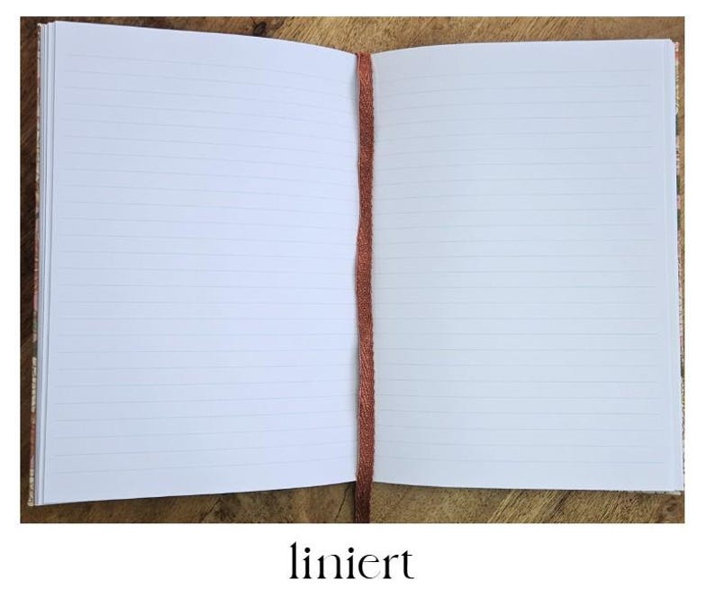 K&ouml;nnte beinhalten: Ein offenes Notizbuch mit linierten Seiten und einem rostfarbenen Band als Lesezeichen. Das Notizbuch liegt auf einer Holzoberfl&auml;che. Das Wort "liniert" steht in Schwarz am unteren Bildrand.