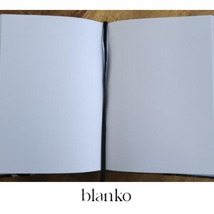 May include: Open blank notebook with a black bookmark. The notebook has a patterned cover with floral and geometric designs in shades of brown, blue, and red. The word "blanko" is printed at the bottom.