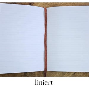 Puede incluir: Un cuaderno abierto con p&aacute;ginas rayadas y una cinta de color &oacute;xido como marcador. El cuaderno est&aacute; sobre una superficie de madera. La palabra "rayado" est&aacute; escrita en negro en la parte inferior de la imagen.