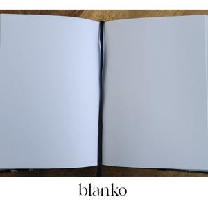 K&ouml;nnte beinhalten: Offenes Notizbuch mit leeren Seiten und einem schwarzen Lesezeichen. Der Einband hat ein Blumenmuster in Braun-, Blau- und Rott&ouml;nen. Das Wort "blanko" ist unten in Schwarz gedruckt.