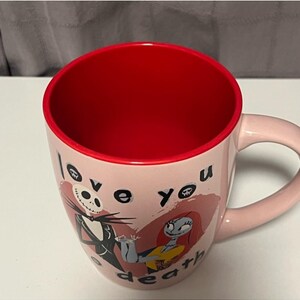 May include: Pink ceramic mug with a red interior featuring Jack Skellington and Sally from The Nightmare Before Christmas. The mug has the words "love you death" printed on it.