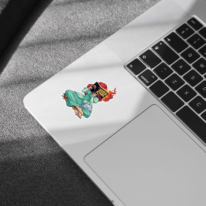 A sticker depicting a person reading a book is placed on the side of a laptop keyboard.