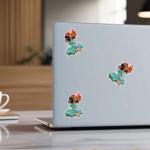 a laptop with three stickers on its back cover, each depicting a cartoon character.