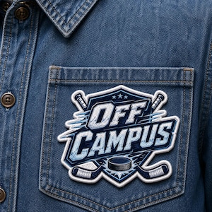 May include: A blue and white embroidered patch with the words "OFF CAMPUS" and hockey-related graphics. The patch is on a denim shirt pocket. The design includes crossed hockey sticks, a puck, and stars.