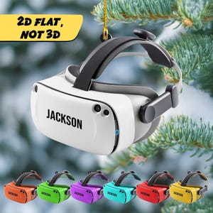 May include: A white and black VR headset with the name "JACKSON" printed on the front. The image also shows six colorful miniature VR headsets in orange, green, purple, teal, red, and yellow. Text in the image reads "2D FLAT, NOT 3D."