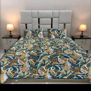 May include: A bed with a patterned comforter and two matching pillowcases. The bedding features a botanical design with green, orange, and white leaves and flowers on a dark teal background. The headboard is a light gray color.