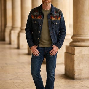 May include: A dark wash denim jacket with a colorful patterned yoke, paired with a green t-shirt and dark blue jeans. The jacket has button closures and pockets. The outfit is completed with black boots.