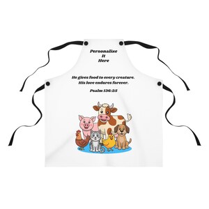 May include: White apron with a colourful illustration of farm animals, including a pig, cow, dog, cat, chicken, and the text "He gives food to every creature. His love endures forever. Psalm 136:25." The apron has black ties and the text "Personalize It Here".
