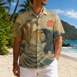 May include: A short-sleeve button-down shirt featuring a beige background with a graphic print of a three-headed dragon and a large monster facing each other. The design includes blue ocean waves, a mountain, and a large red sun in the background.