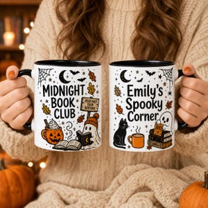 May include: Two white ceramic mugs with black rims and handles. The left mug features the text 'MIDNIGHT BOOK CLUB' with a jack-o'-lantern, a ghost, and autumn leaves. The right mug displays 'Emily's Spooky Corner' with a black cat and a ghost.