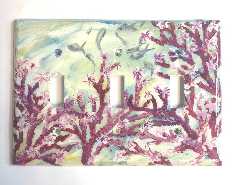 Ocean theme hand-painted on a three toggle light switch plate cover with pink blooming coral and light grey color fish set against a blended light green color background. Artwork is protected with a resin glaze to ensure durability and give a glass like finish. Signed by Artist TDavis. Made to order with a variety of wall plate sizes available. Allow 10-14 days studio time