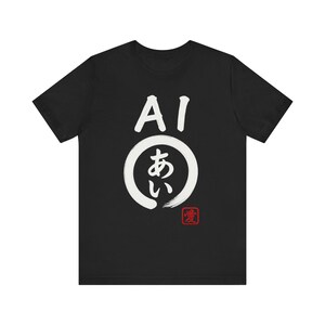 以下が含まれることがあります： 黒いTシャツ。白い日本語の文字と「AI」の文字が描かれ、その下に円形のデザインがあります。円の下には、小さな赤い正方形に日本語の文字が描かれています。カジュアルウェアアイテムです。