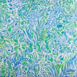 May include: A white fabric with a blue and green pattern of leaves, flowers, and animals. The animals include lions, leopards, and elephants.