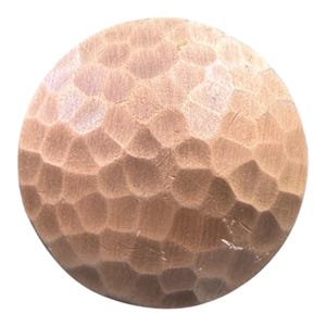 Op de afbeelding: Een ronde houten knop met een gehamerde textuur. De knop heeft een warme, roodbruine kleur en heeft een reeks onregelmatige, geometrische vormen die in het oppervlak zijn gesneden. Het ontwerp is rustiek en handgemaakt.