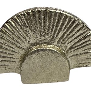 May include: A silver-coloured, fan-shaped cabinet knob with a textured surface. The knob has a semi-circular top with radiating lines and a rectangular base. This decorative hardware is suitable for drawers and cabinets.