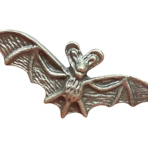 以下が含まれることがあります： 銀色のコウモリの置物。翼を広げたコウモリは、翼と顔にテクスチャが施されており、ゴシックまたはハロウィーンをテーマにしています。白い背景に分離されています。