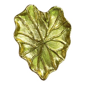 May include: A gold-coloured leaf-shaped decorative dish with a textured surface. The dish has a detailed vein pattern and a metallic finish, ideal for holding small items or as a decorative accent.