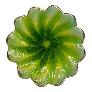 May include: A decorative, scalloped-edge dish in shades of green and yellow. The dish has a crackled texture and a gold-coloured rim. The design resembles a flower or leaf.