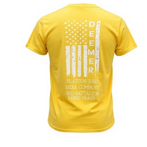 May include: Yellow t-shirt with a white American flag design on the back. The flag design includes stars and stripes, with the word "DEEMER" vertically aligned. Below the flag are the words "PLATOON 3050 INDIA COMPANY 3RD BATTALION PARES ISLAND."
