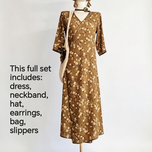 May include: A complete outfit on a mannequin, including a brown floral print dress, hat, earrings, bag, and slippers. The dress has a V-neck and three-quarter sleeves. The text on the left says "This full set includes: dress, neckband, hat, earrings, bag, slippers."