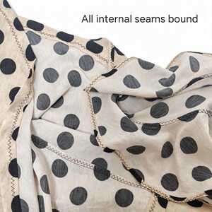May include: A cream-colored fabric featuring a black polka dot pattern with all internal seams bound by a beige trim and finished with a dark zigzag stitch. The text "All internal seams bound" is clearly visible at the top of the image.