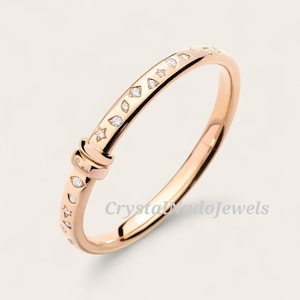 May include: Rose gold bangle bracelet with star, diamond, and eye-shaped accents. The bracelet features a clasp design and is adorned with small, sparkling gemstones. The text "Crystal Mondo Jewels" is visible on the bracelet.