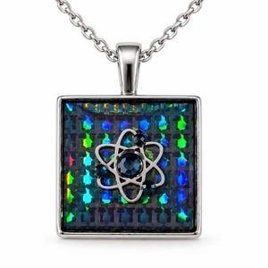 Puede incluir: Un collar con colgante cuadrado de plata que presenta un diseño de átomo central. El átomo está acentuado con cristales azul oscuro. El fondo del colgante tiene un patrón de rejilla oscuro e iridiscente que refleja luz verde y azul.