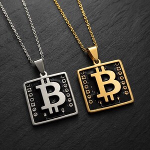 May include: Two square pendants on thin metal chains. One pendant is silver-toned and the other is gold-toned. Each features a central Bitcoin symbol set against a black square background with small circular details resembling a circuit board.