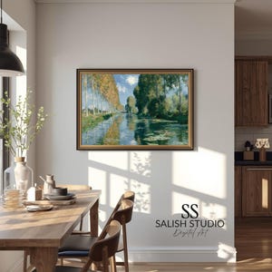 Könnte beinhalten: Gerahmtes Landschaftsgemälde, das eine ruhige Flussszene mit hohen Bäumen an den Ufern zeigt. Das Kunstwerk hat einen goldenen Rahmen und wird in einem Esszimmer ausgestellt. Der Stil des Gemäldes erinnert an den Impressionismus.