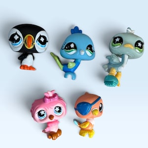 May include: A collection of five small animal figurines with oversized eyes. The set includes a black and white puffin, a blue bird with a green tail, a light blue ostrich, a pink bird with a bow, and a tan bird wearing a blue eye patch.