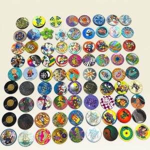 May include: A large collection of circular pogs and slammers arranged in a grid. These game pieces feature a wide variety of colorful graphic designs, including cartoon characters, abstract patterns, animals, and text, with some having metallic finishes.